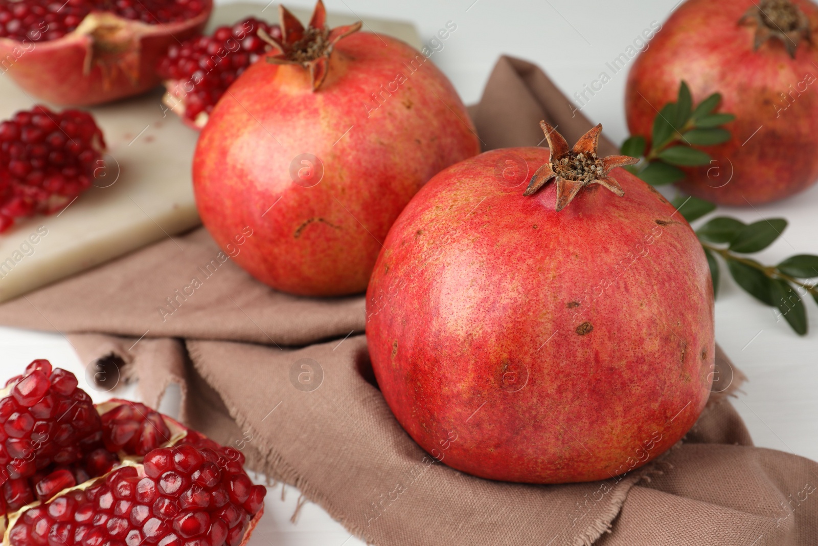 Photo of Fresh pomegranates and seeds on white table, closeup