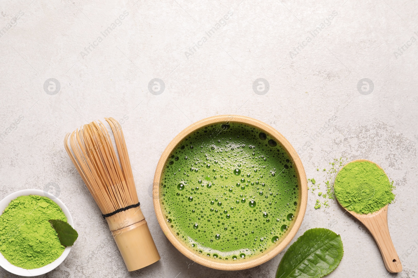 Photo of Bowl of fresh matcha tea, bamboo whisk and powder on light table, flat lay. Space for text