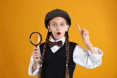 Photo of Cute little detective with magnifying glass on yellow background