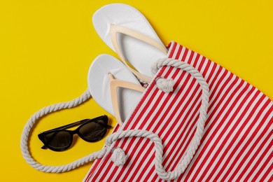 Photo of Flat lay composition with bag and other beach accessories on yellow background