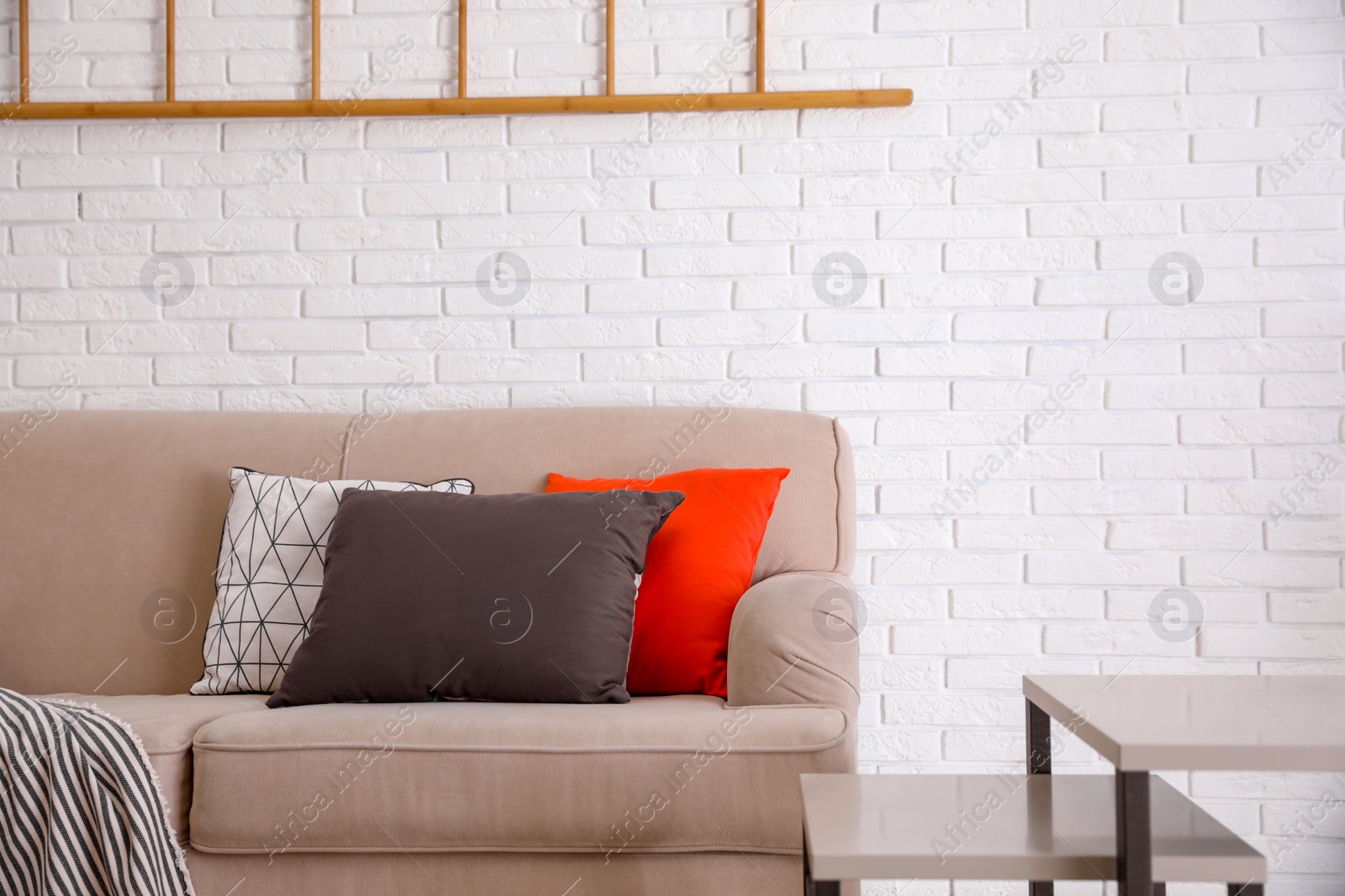 Photo of Soft pillows on sofa near white brick wall