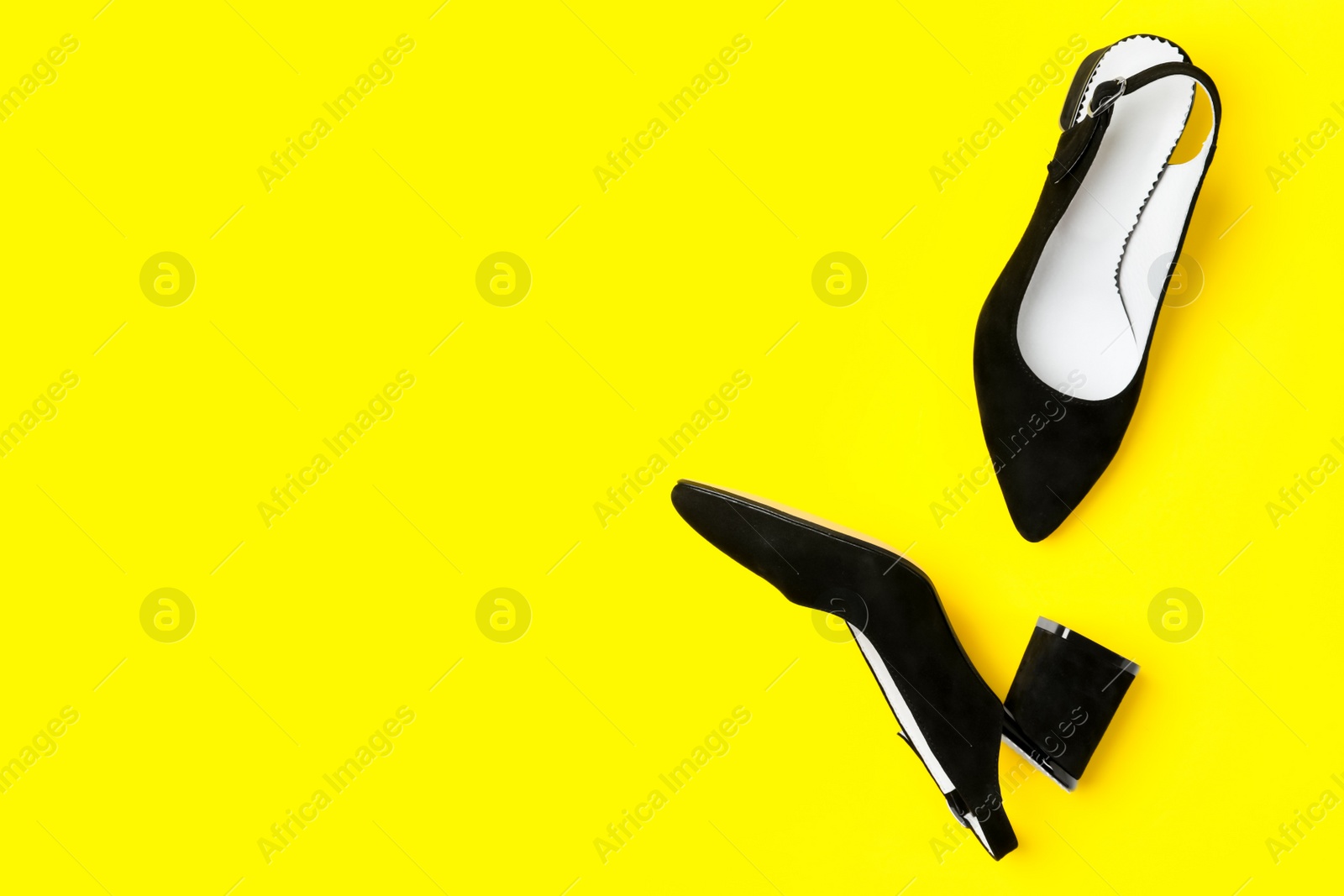 Photo of Stylish black female shoes on yellow background, flat lay. Space for text