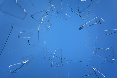 Image of Broken glass with cracks on blue background