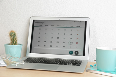 Photo of Modern laptop with calendar app in office