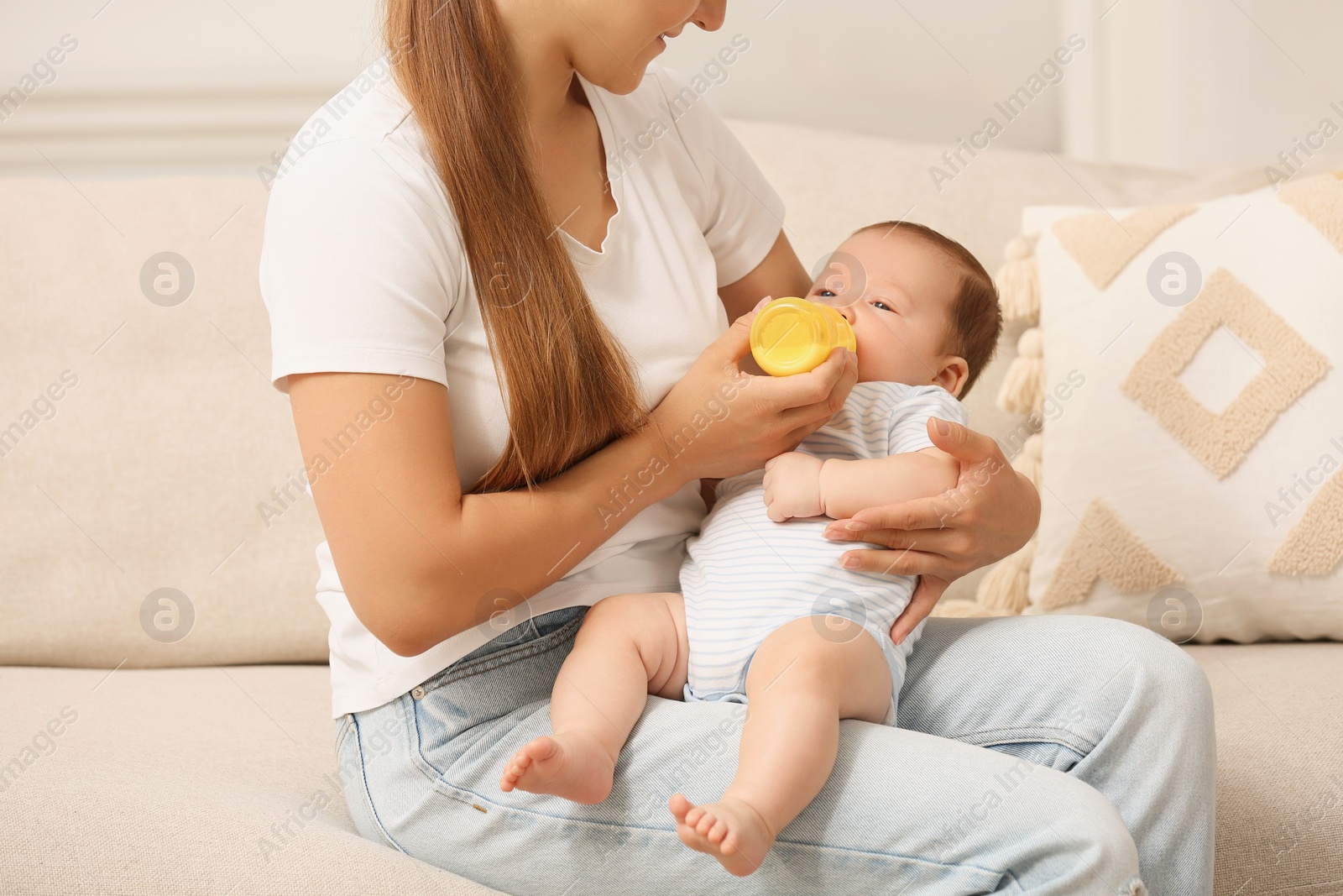 Photo of Mother feeding her cute child with infant formula indoors