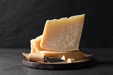 Delicious parmesan cheese with knife on black table