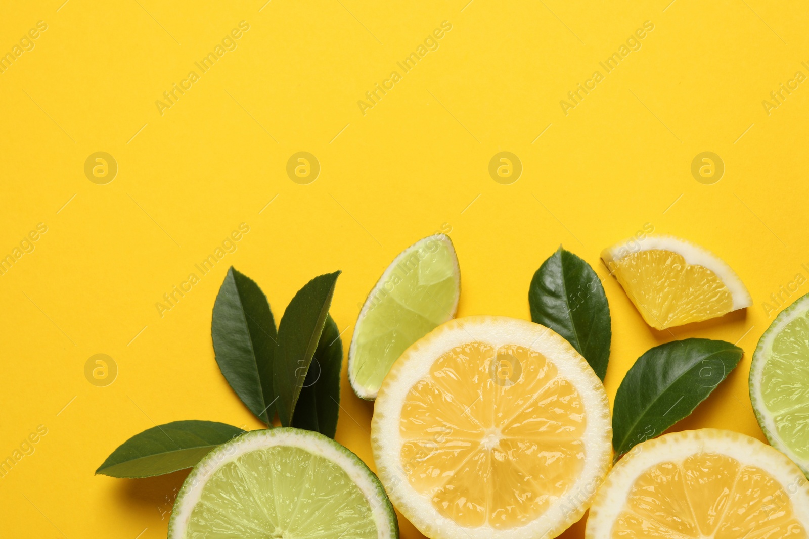 Photo of Fresh ripe lemons, limes and green leaves on yellow background, flat lay. Space for text