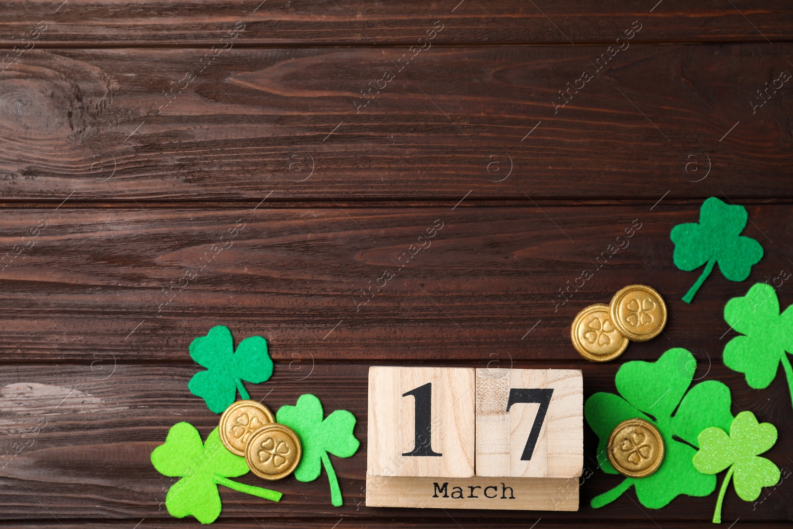 Photo of Flat lay composition with block calendar on wooden background, space for text. St. Patrick's Day celebration