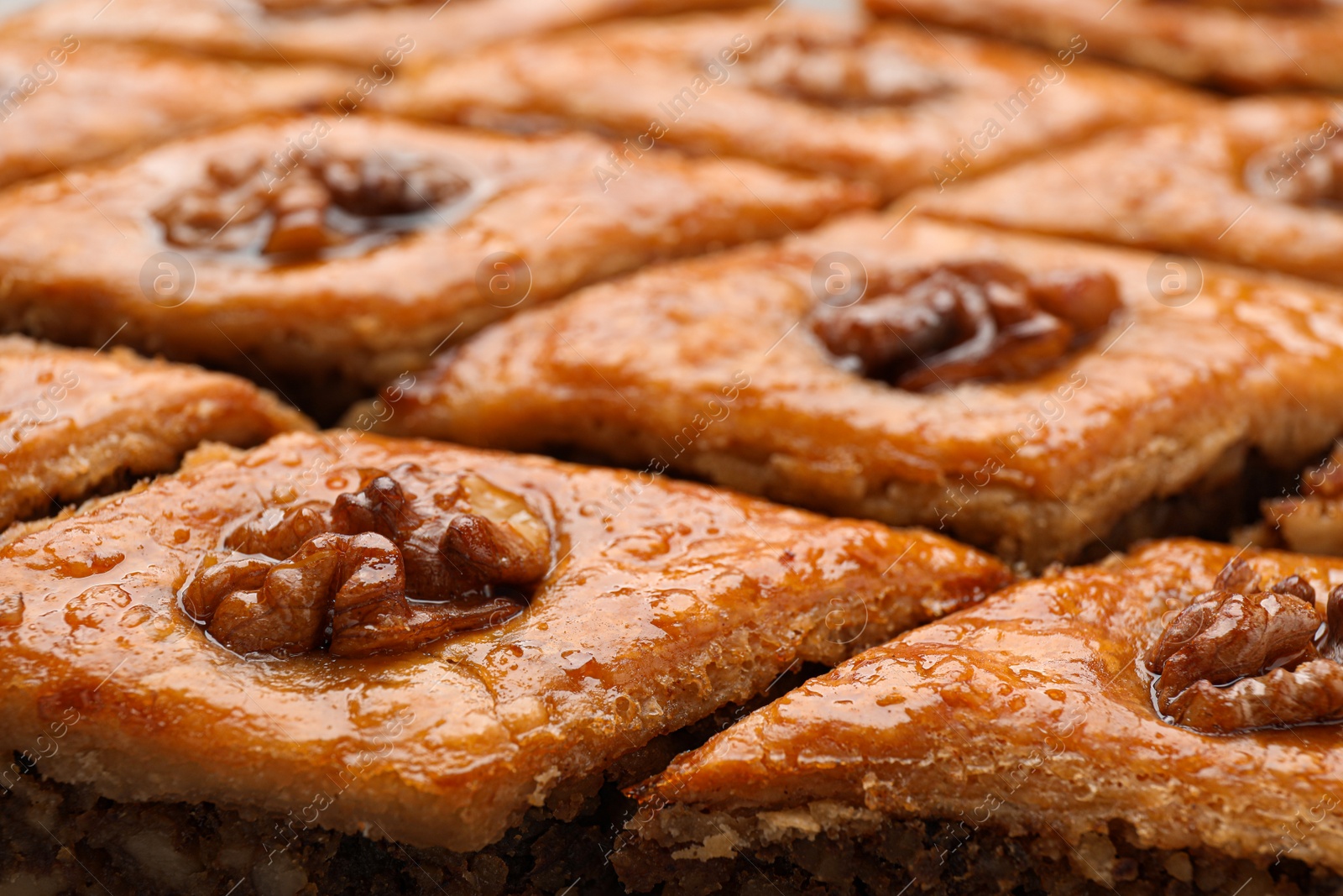 Photo of Delicious honey baklava with walnuts as background, closeup