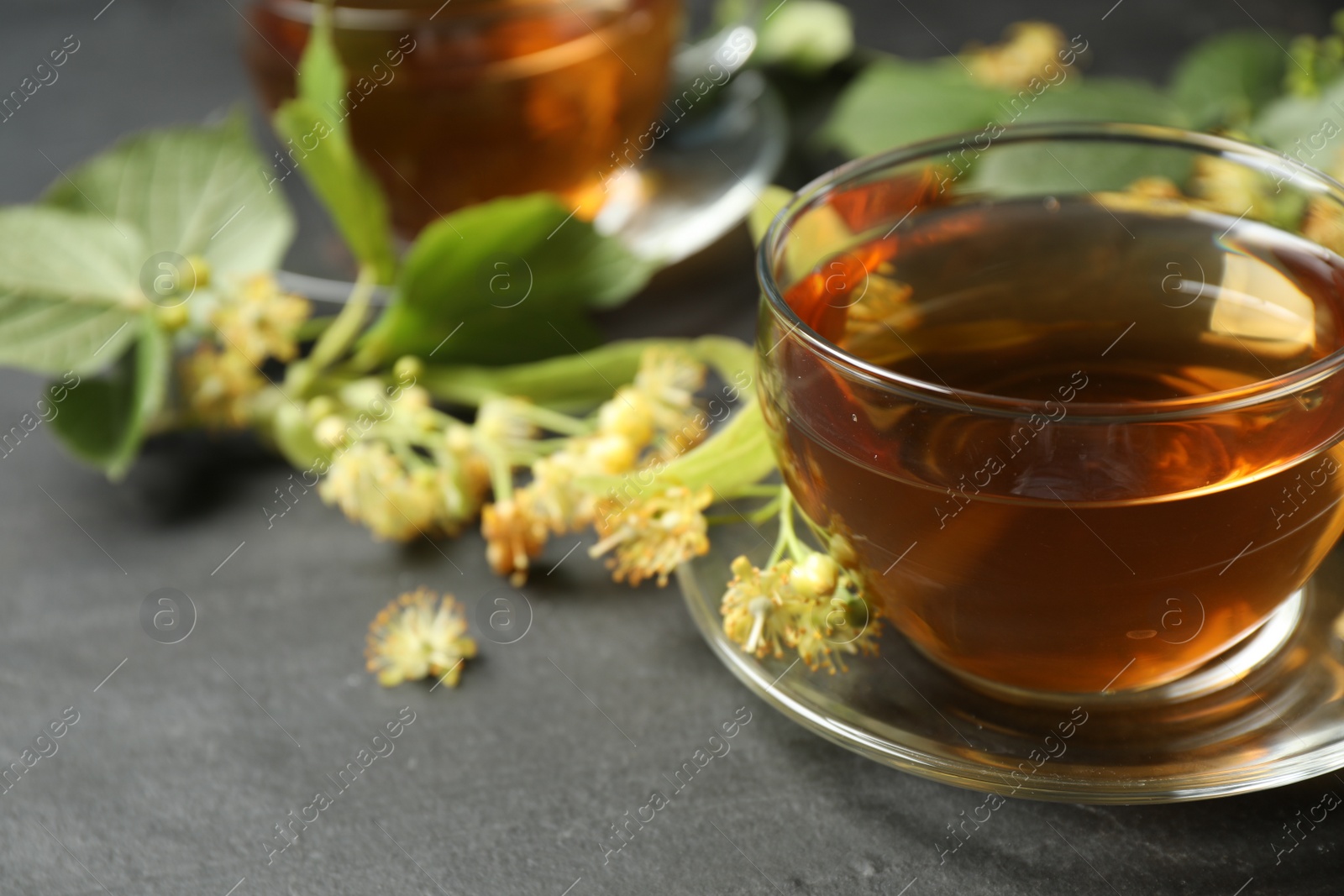Photo of Tasty tea and linden blossom on black table