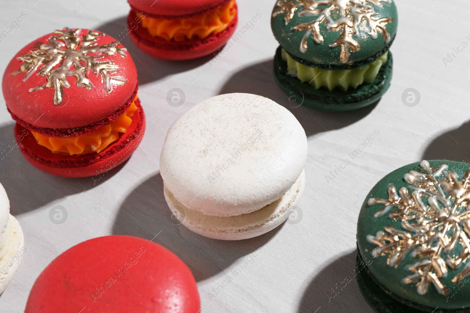 Photo of Different decorated Christmas macarons on wooden table, closeup