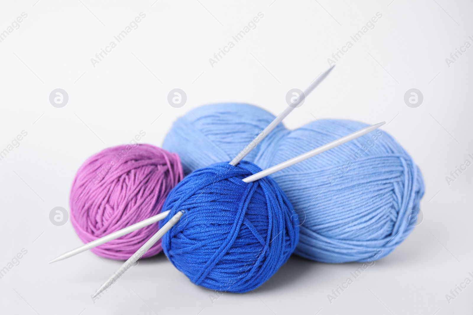 Photo of Soft woolen yarns and knitting needles on white background