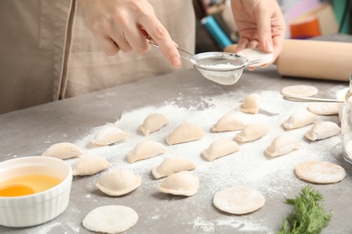 Photo of Woman cooking delicious dumplings at table, closeup