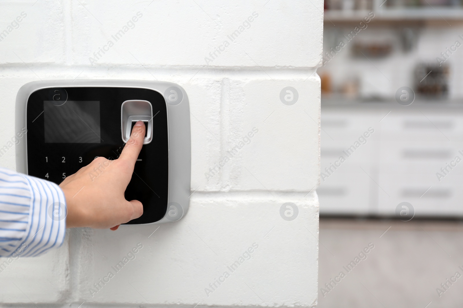 Photo of Woman scanning fingerprint on alarm system at home, closeup. Space for text