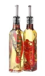 Photo of Glass bottles of cooking oil with spices and herbs on white background