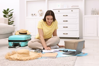 Travel blogger with book and other items planning trip at home