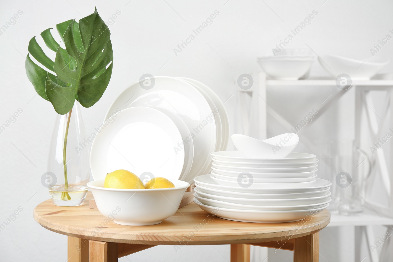 Photo of Different clean tableware on wooden table in kitchen