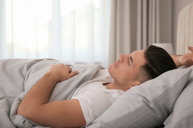 Photo of Man sleeping in bed with grey linens at home