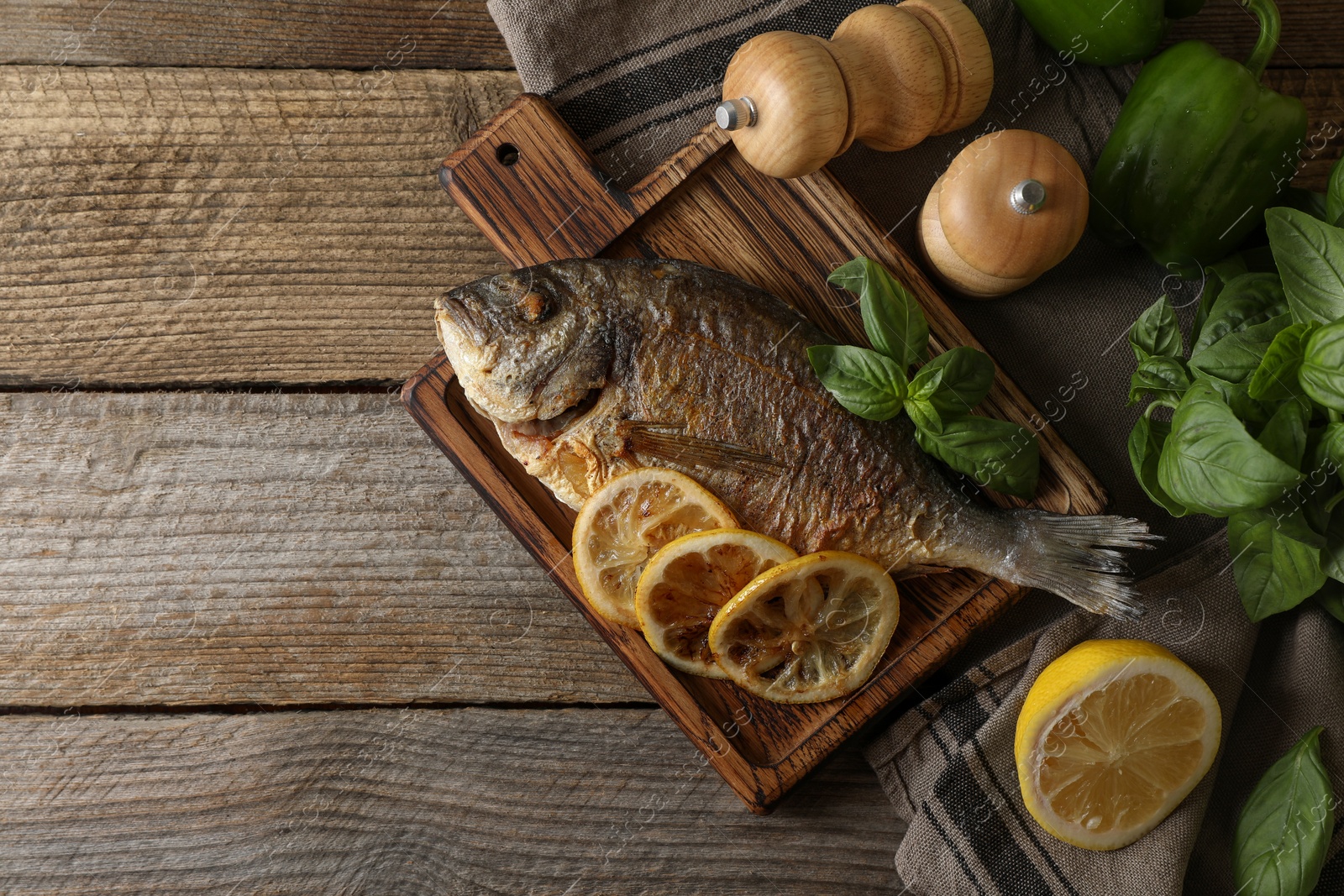 Photo of Delicious dorado fish served on wooden table, flat lay. Space for text