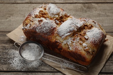 Photo of Delicious yeast dough cake and strainer with powdered sugar on wooden table