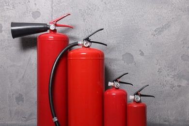 Photo of Four red fire extinguishers near grey wall