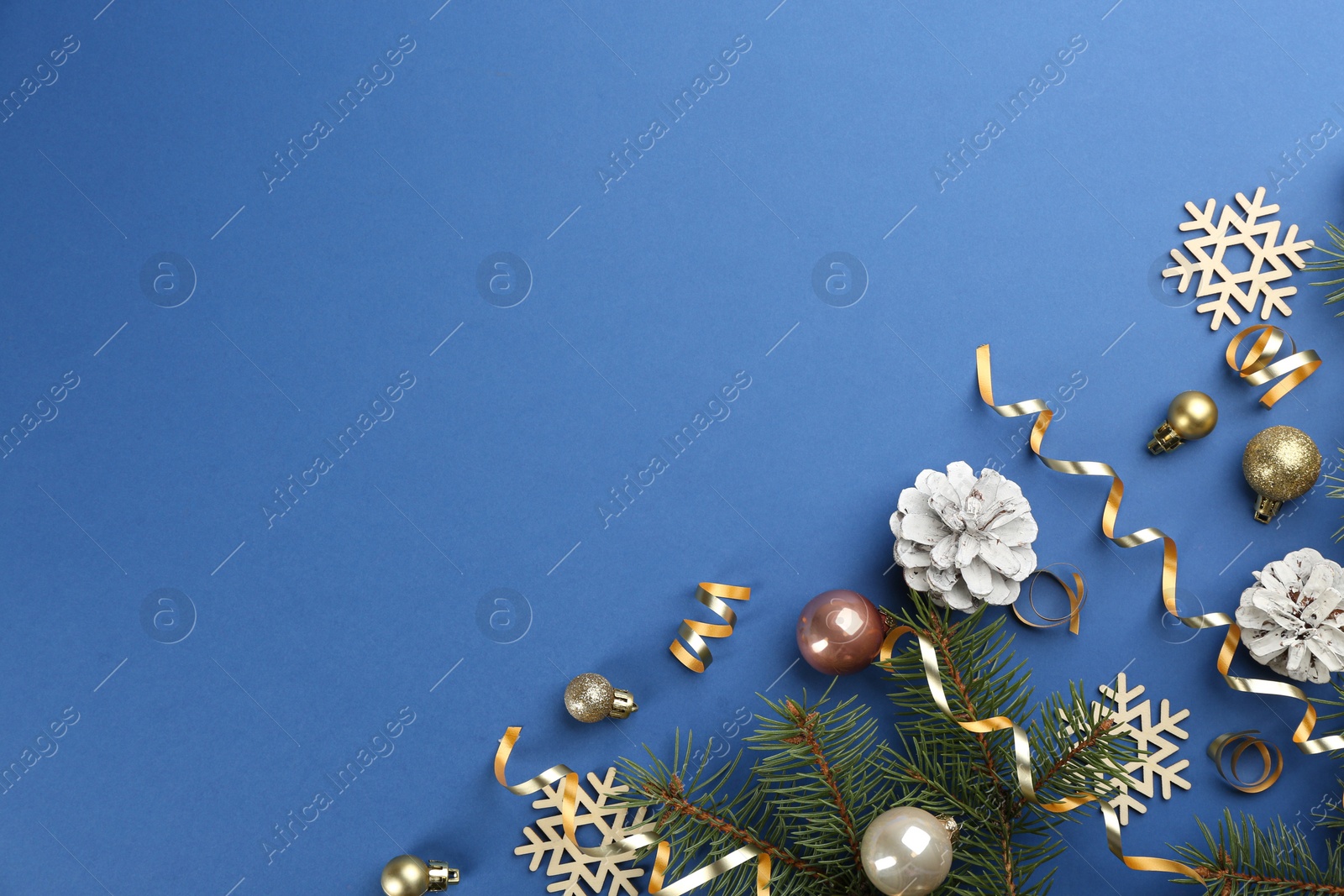 Photo of Flat lay composition with serpentine streamers and Christmas decor on blue background. Space for text
