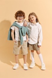 Photo of Fashion concept. Stylish children on pale orange background