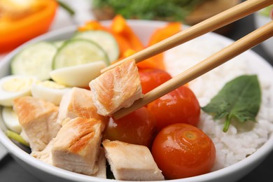 Photo of Delicious poke bowl with meat, rice, eggs and vegetables, closeup