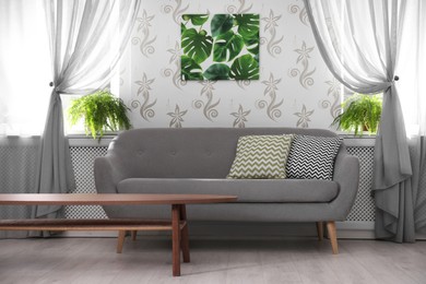 Stylish interior. Comfortable sofa, side table and houseplants in living room
