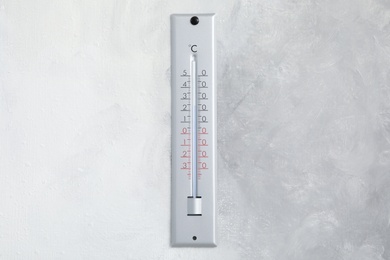 Weather thermometer hanging on light grey wall