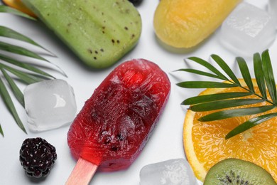Photo of Delicious popsicles, fresh fruits and ice cubes on light background, closeup