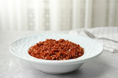 Photo of Plate with delicious cooked brown rice on grey table