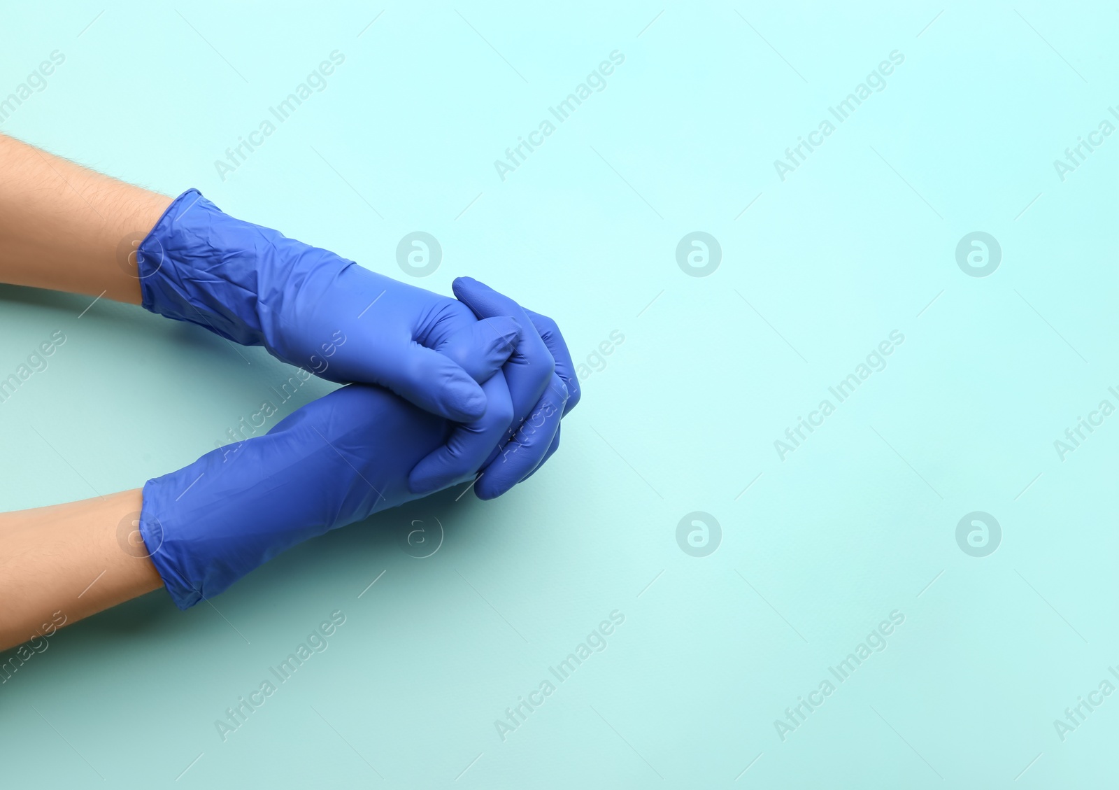 Photo of Person in medical gloves on light blue background, top view. Space for text