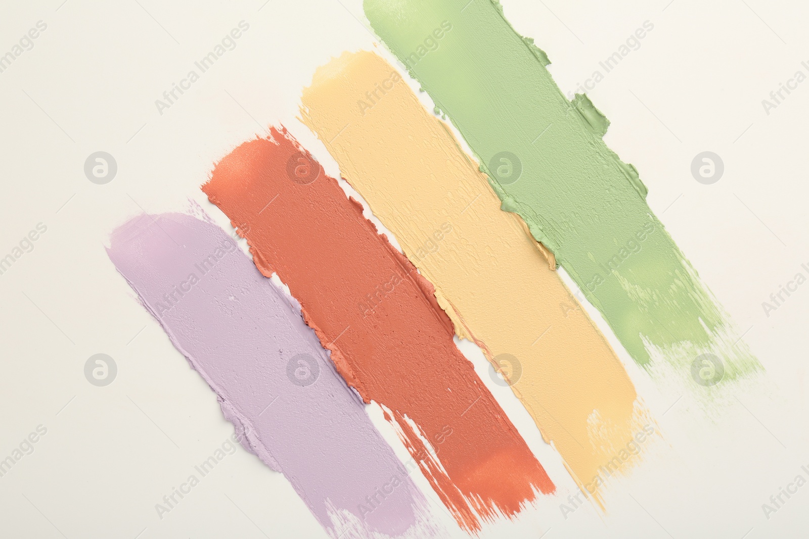 Photo of Samples of different color correcting concealers on white background, top view