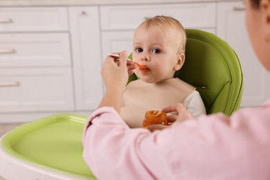 Photo of Mother feeding her cute little baby with healthy food at home
