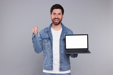 Photo of Emotional man with laptop on light grey background