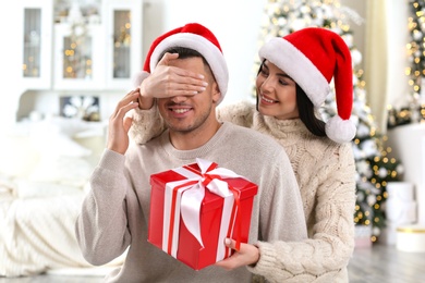 Young woman presenting Christmas gift to her boyfriend at home