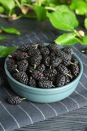 Photo of Delicious ripe black mulberries on dark wooden table