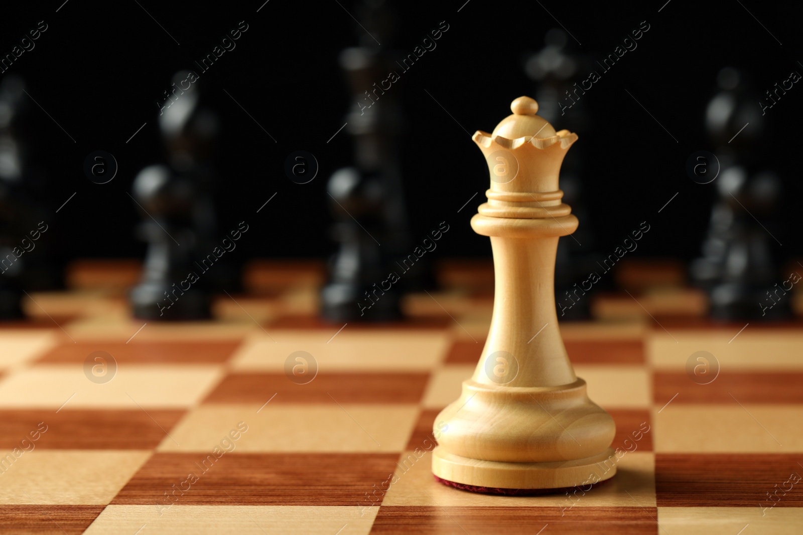 Photo of Chessboard with game pieces on black background, closeup. Space for text