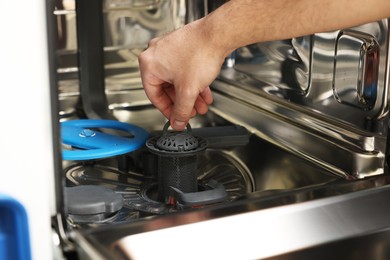 Photo of Repairman pulling drain filter out of dishwasher, closeup