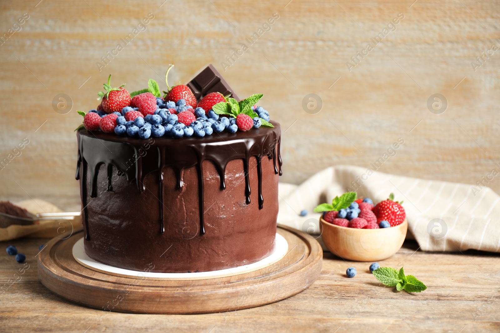 Photo of Freshly made delicious chocolate cake decorated with berries on wooden table