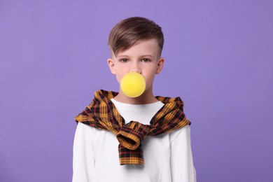 Photo of Boy blowing bubble gum on purple background