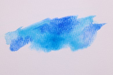 Photo of Blot of blue watercolor paint on white paper, top view