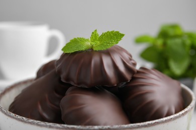 Photo of Delicious chocolate covered zephyrs with mint in bowl, closeup