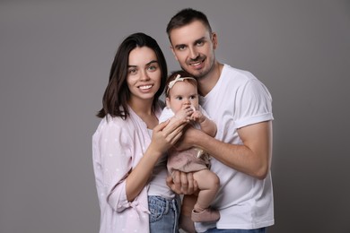 Photo of Happy family. Couple with their cute baby on grey background