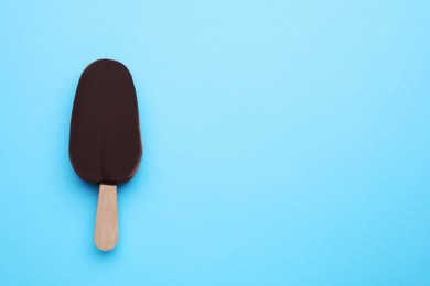 Photo of Delicious glazed ice cream bar on light blue background, top view. Space for text