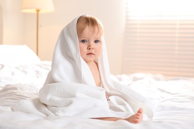 Photo of Cute little baby with soft towel on bed after bath