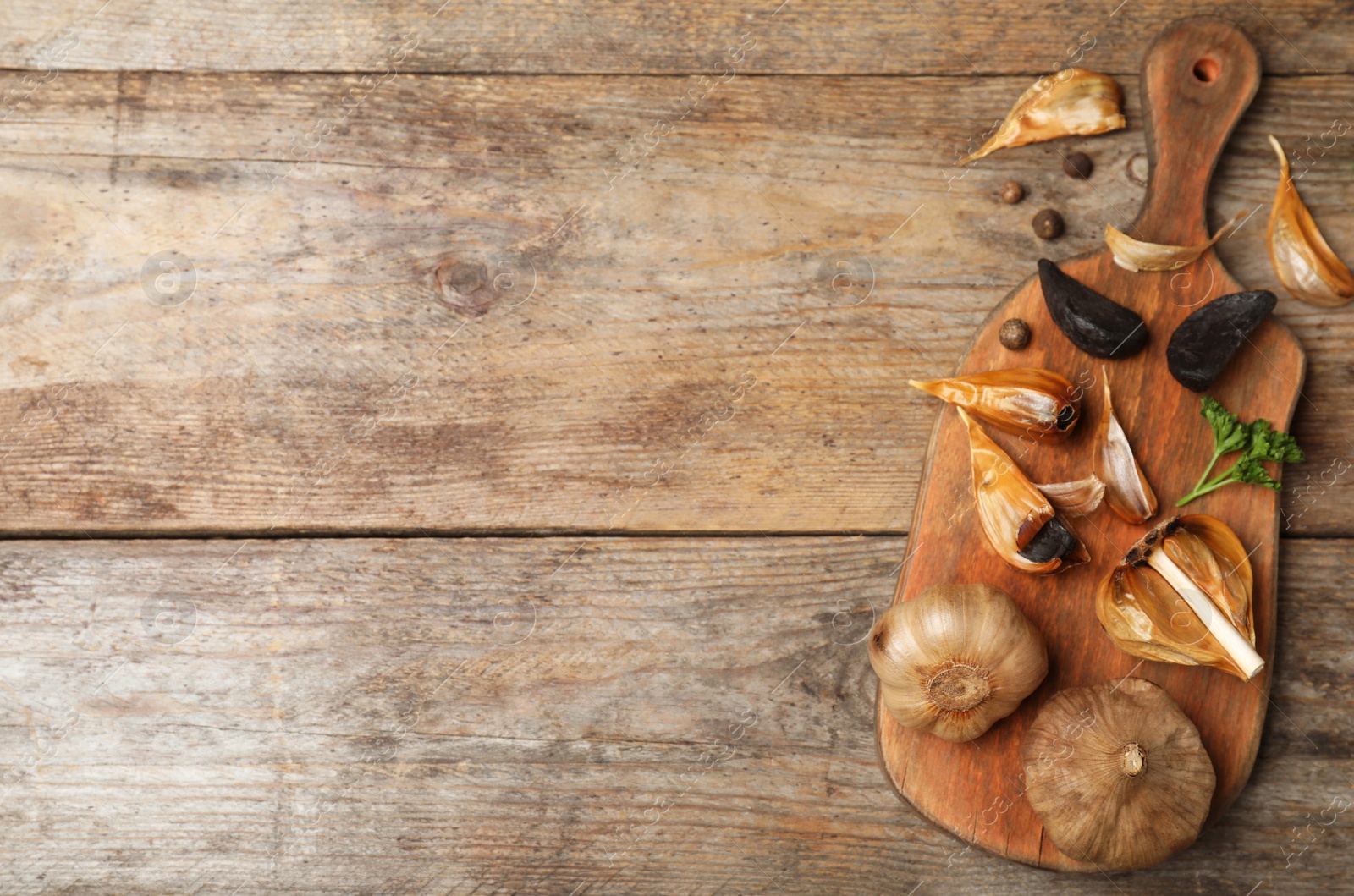 Photo of Flat lay composition with black garlic and space for text on wooden table