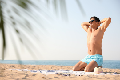 Photo of Happy man with slim body resting on beach. Space for text