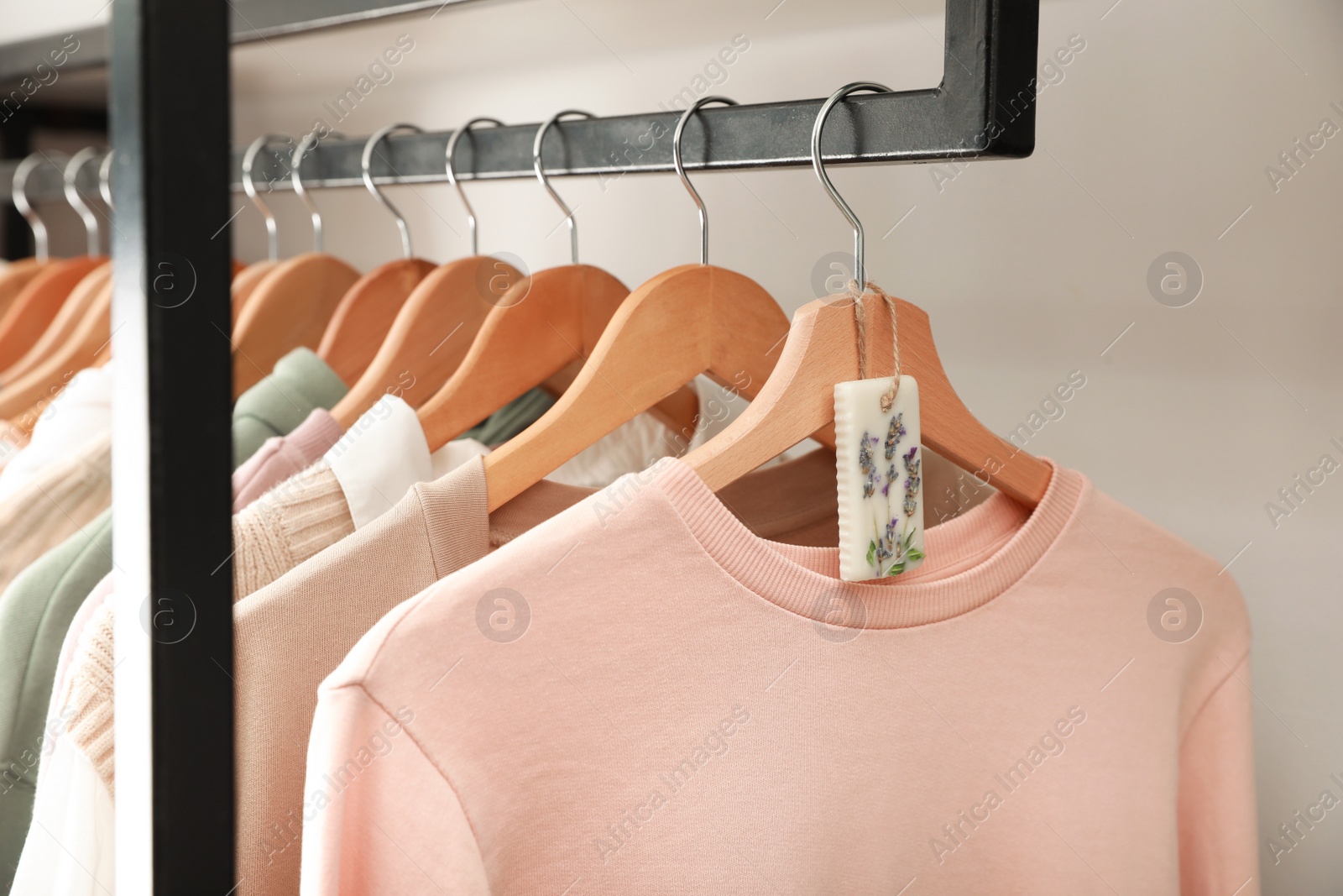 Photo of Beautiful scented sachet and clothes hanging in wardrobe